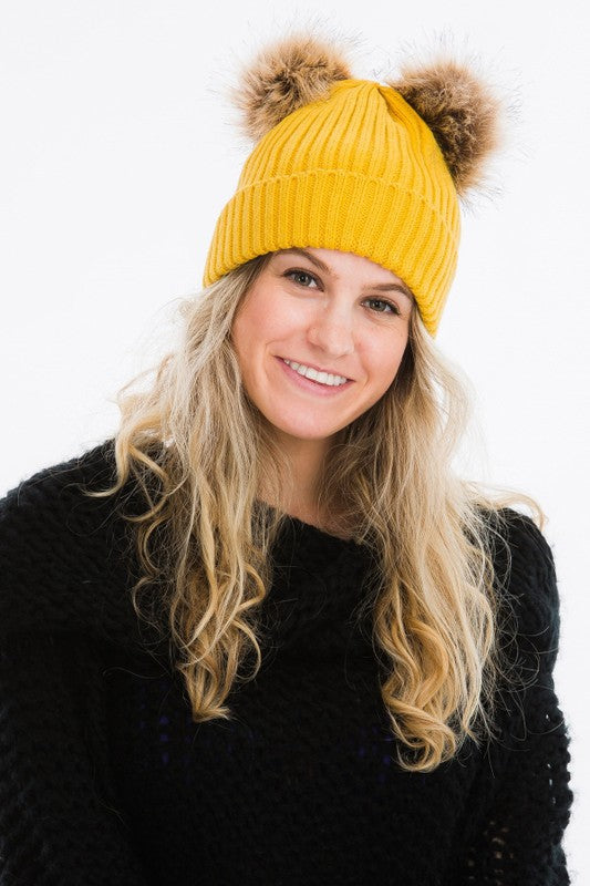mustard winter hat with two pom poms attached